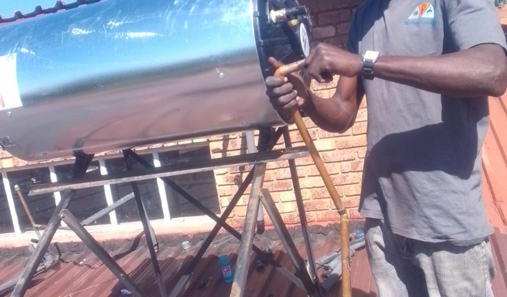 A plumber from Unique Fix repairing a leaking solar geyser on a rooftop.